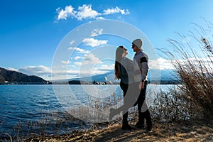 Japan - A couple standing at the side of Kawaguchiko Lake and admiring Mt Fuji