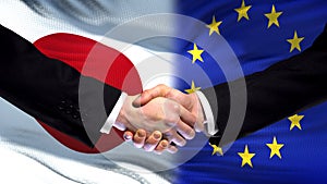 Japan and European Union handshake, international friendship, flag background