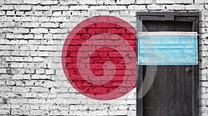 Japan flag painted on brick wall and closed door with medical mask protected