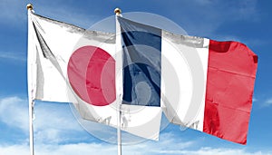 Japan and France flags against cloudy sky.
