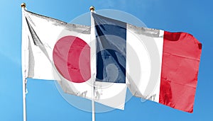 Japan and France flags against cloudy sky.
