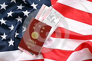 Japan passport with airline tickets on American US flag close up. Tourism and travel