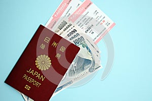 Japan passport with money and airline tickets on blue background close up