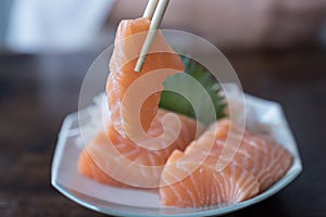 Japan raw salmon slice or salmon sashimi in japanese style. Salmon sasimi on chopsticks