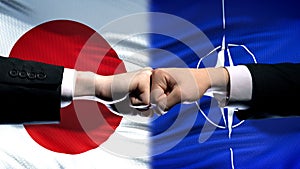 Japan vs NATO conflict, international relations crisis, fists on flag background