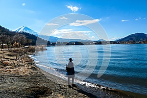 Japan - A woman standing at the side of Kawaguchiko Lake with the view on Mt Fuji