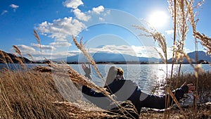 Japan - A woman walking in between golden grass at the shore of Kawaguchiko Lake with the view on Mt Fuji