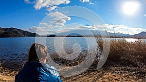 Japan - A woman walking in between golden grass at the shore of Kawaguchiko Lake with the view on Mt Fuji