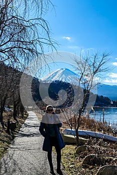 Japan - A woman walking at the side of Kawaguchiko Lake with the view on Mt Fuji