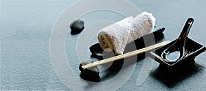 Japanese, asian food utensils - pair of chopsticks, hot weat towel, ceramic black spoon, dark stone. Menu in restaurant