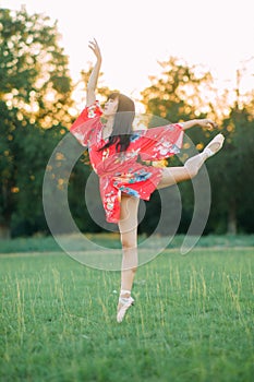 Japanese ballerina in red kimono stands in swallow pose