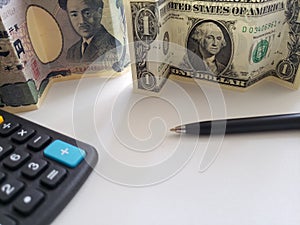 japanese banknote of 1000 yen, American one dollar bill, black pen and calculator photo