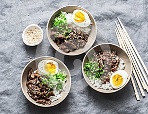 Japanese beef, rice and boiled egg bowl on grey background, top view. Asian food concept