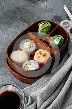 Japanese bento lunch box with chopsticks, on gray stone background