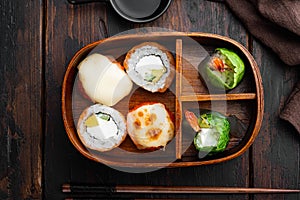Japanese bento lunch box with chopsticks, on old dark  wooden table background, top view flat lay