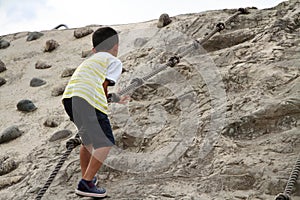 Japanese boy climbing on the wall