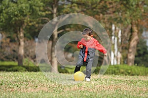 Japanese boy kicking a yellow ball