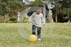 Japanese boy kicking a yellow ball