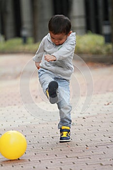 Japanese boy kicking a yellow ball