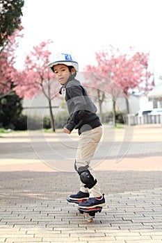 Japanese boy riding on a casterboard
