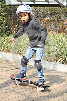 Japanese boy riding on a casterboard