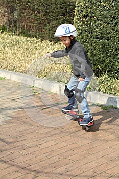 Japanese boy riding on a casterboard