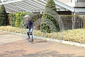 Japanese boy riding on a casterboard