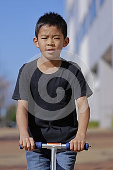 Japanese boy riding on a scooter