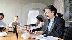 Japanese Businessman Using Tablet Sitting At Corporate Meeting Indoor, Panorama