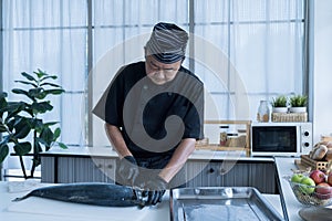 Japanese chef cleaning salmon. A worker cutting salmon on a board