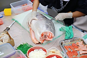 Japanese chef slicing raw fish for salmon sushi. Chef preparing a fresh salmon on a cutting board