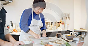 Japanese chef, woman and kitchen with knife, cooking and prepare ingredients for catering services. Person, food and