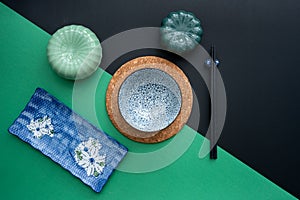 Japanese or Chinese table setting with traditional table mat and dinnerware with green and black background.