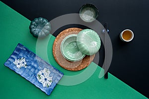 Japanese or Chinese table setting with traditional table mat and dinnerware with green and black background.