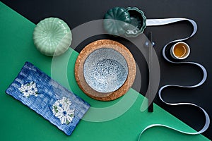Japanese or Chinese table setting with traditional table mat and dinnerware with green and black background.