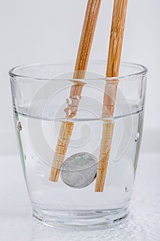 Japanese coin yen holding by wooden chopsticks in a glass of w