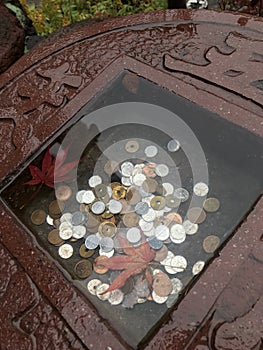 Japanese coins in little stone basin of a shrine.