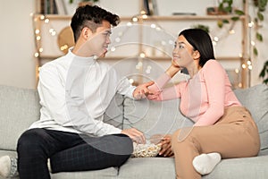 Japanese Couple Talking Enjoying Conversation Eating Popcorn Sitting At Home