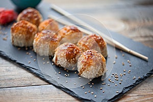 Japanese cuisine. Baked sushi with crab meat and cheese on a stone slab in a dark wood background