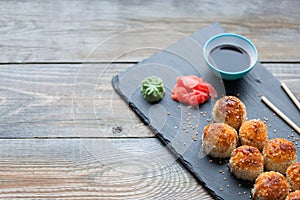 Japanese cuisine. Baked sushi with crab meat and cheese on a stone slab in a dark wood background. Top view with copy space