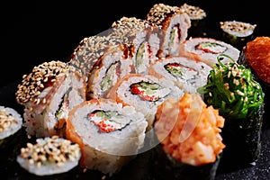 Japanese cuisine. Close up of delicious sushi rolls with various fillings on dark background.