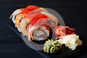 Japanese cuisine. Japanese sushi with soy sauce and wasabi on black stone plate on black background