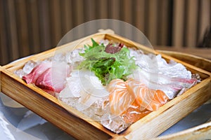 Japanese cuisine sashimi salmon and raw fish sashimi salad on ice served on wooden tray in the Japanese food restaurant
