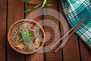 Japanese cuisine, soup with chashu pork, chives, sprouts, noodles and seaweed on the table under the sunlight. Wooden rustic backg