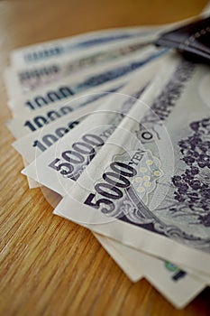 Japanese currency (yen) with its Asian symbols in form bank notes on the wooden background