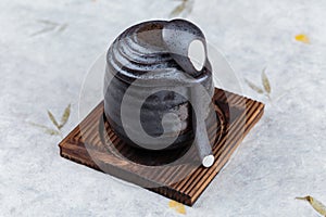 Japanese custard pudding torched caramel on top served in black ceramic cup on wooden plate with lid and spoon on washi.