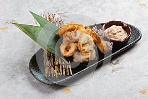 Japanese deep fried squid mixing tempura flour Squid Karaage served with sauce in black plate washi Japanese paper photo
