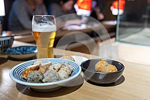 Japanese dumplings and fish ball on a plate with a glass of beer.