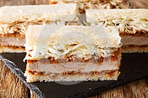 Japanese fast food katsu sando sandwiches with tonkatsu sauce and cabbage closeup on a slate board. horizontal photo