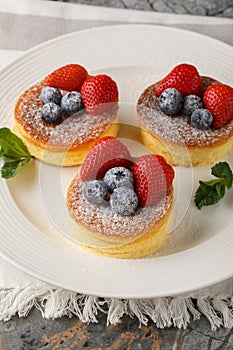 Japanese fluffy pancakes with fresh berries close-up on a plate. Vertical